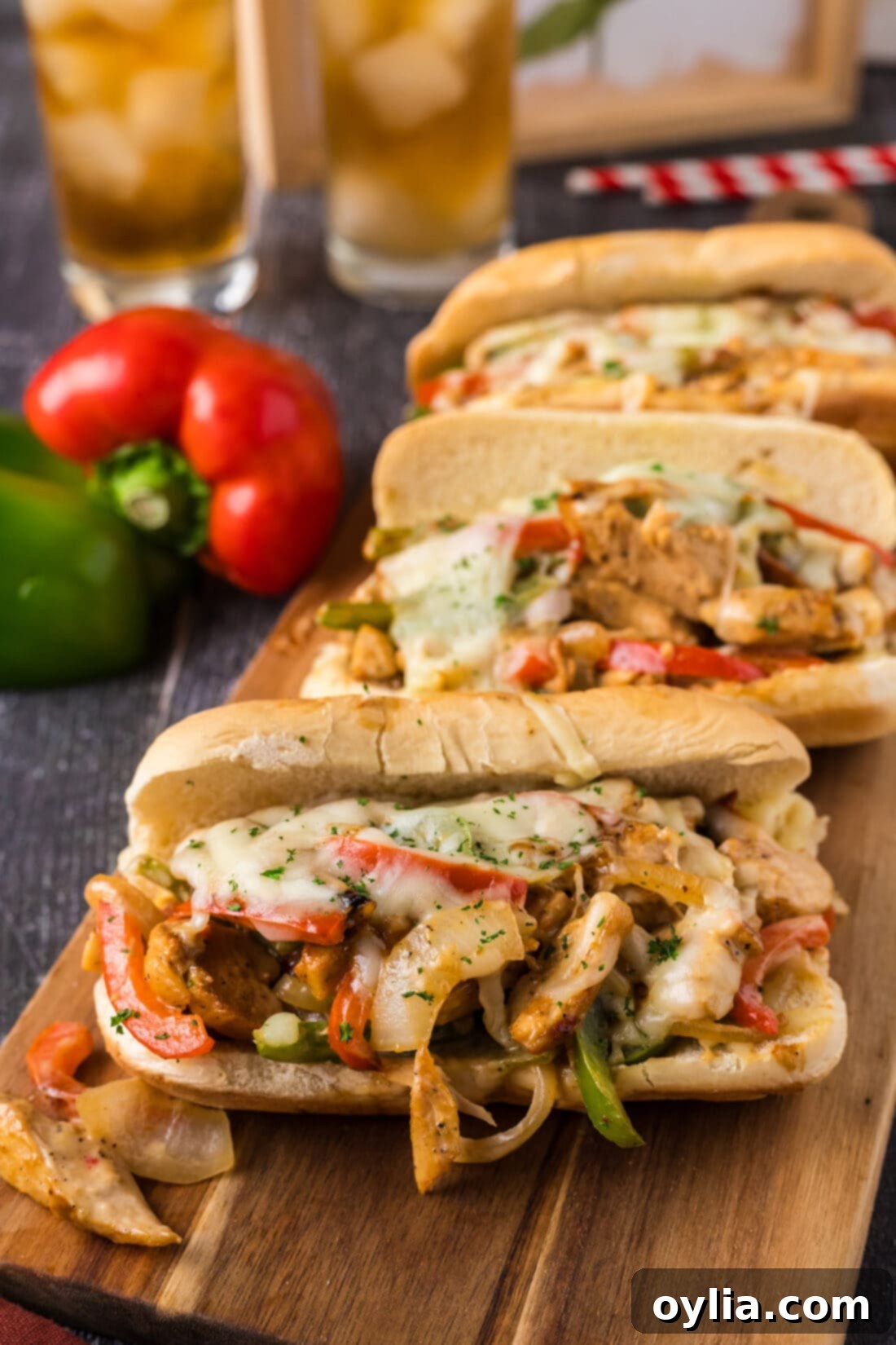 Ultimate Chicken Philly 1 Three Chicken Philly Cheesesteaks on a wooden serving board