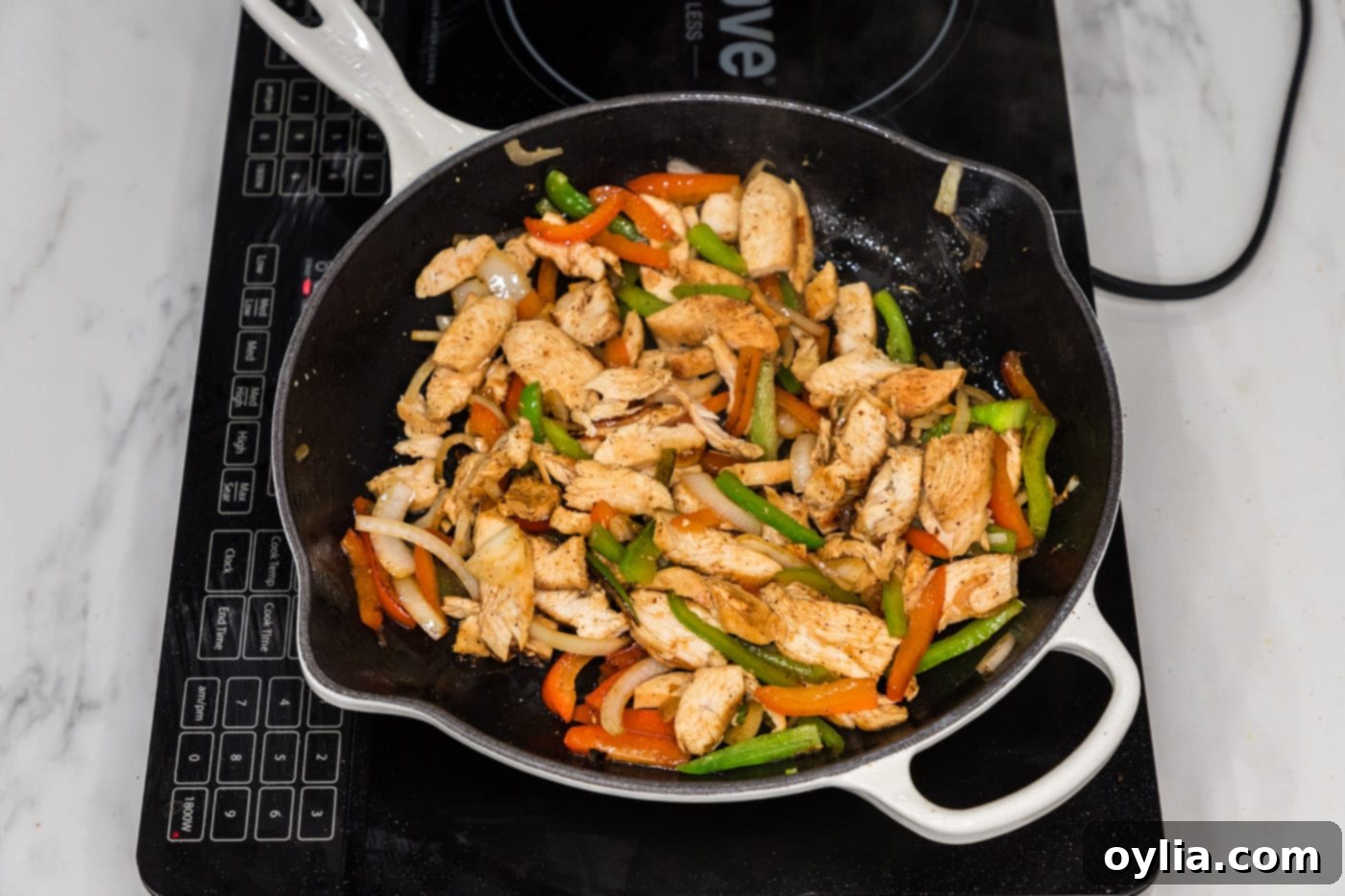 sliced chicken added to skillet with bell peppers and onion