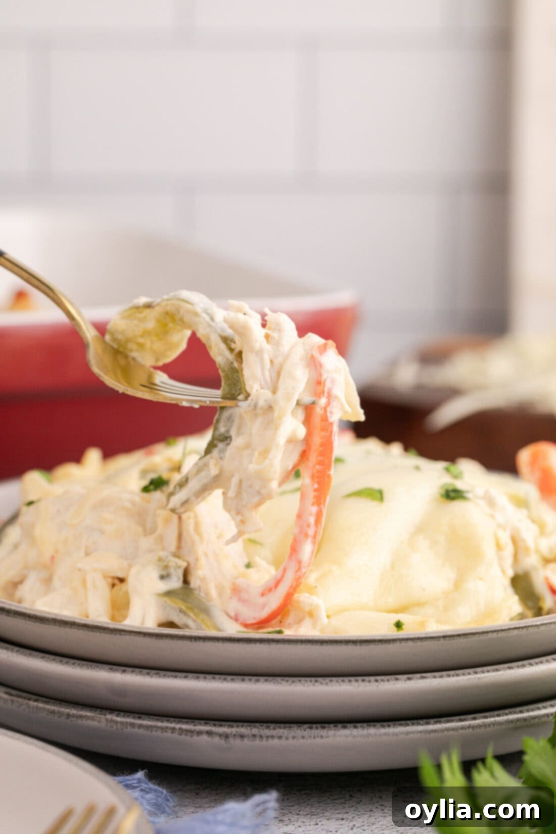 Forkful of Philly Chicken Cheesesteak Casserole held above a plate, showing the melted cheese and chicken