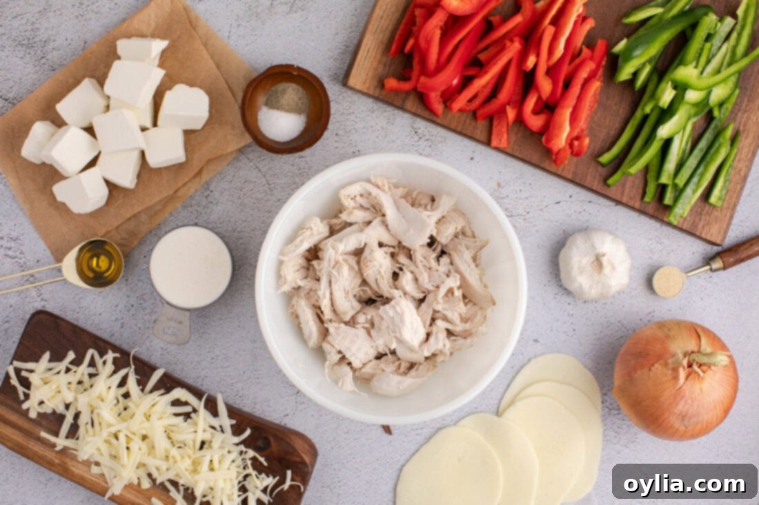 Ingredients laid out for Philly Chicken Cheesesteak Casserole, including chicken, cheeses, peppers, and onions