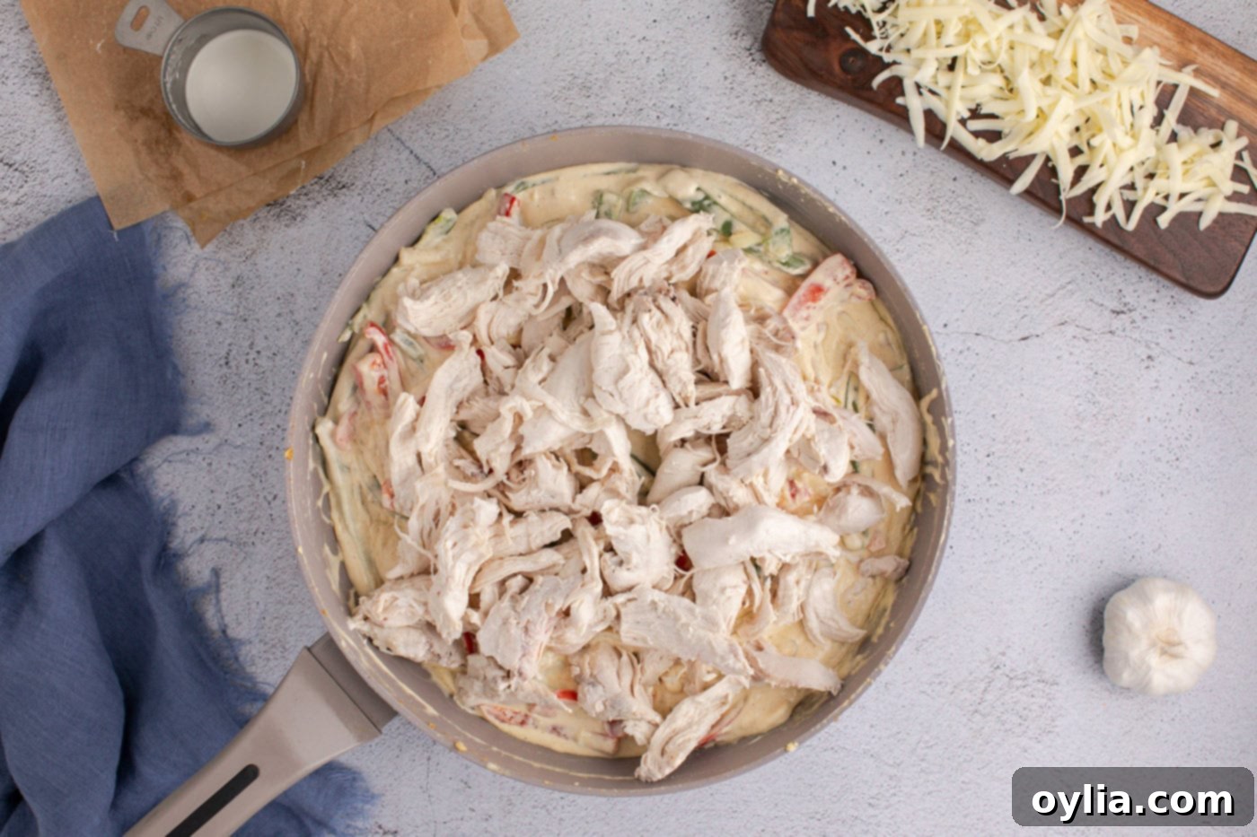 shredded chicken thoroughly mixed in skillet with creamy sauce, peppers, and onions
