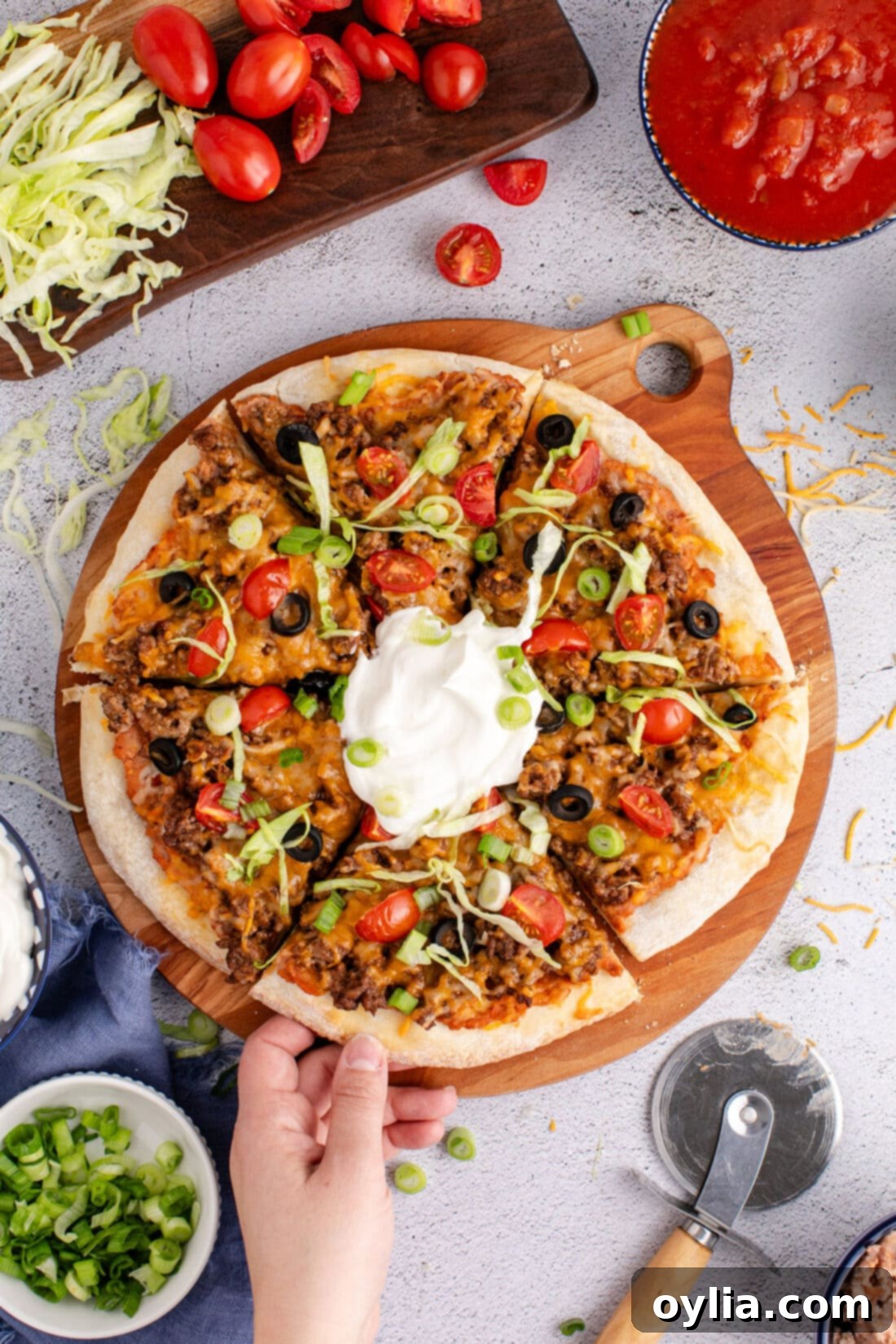 Hand grabbing a slice of Taco Pizza