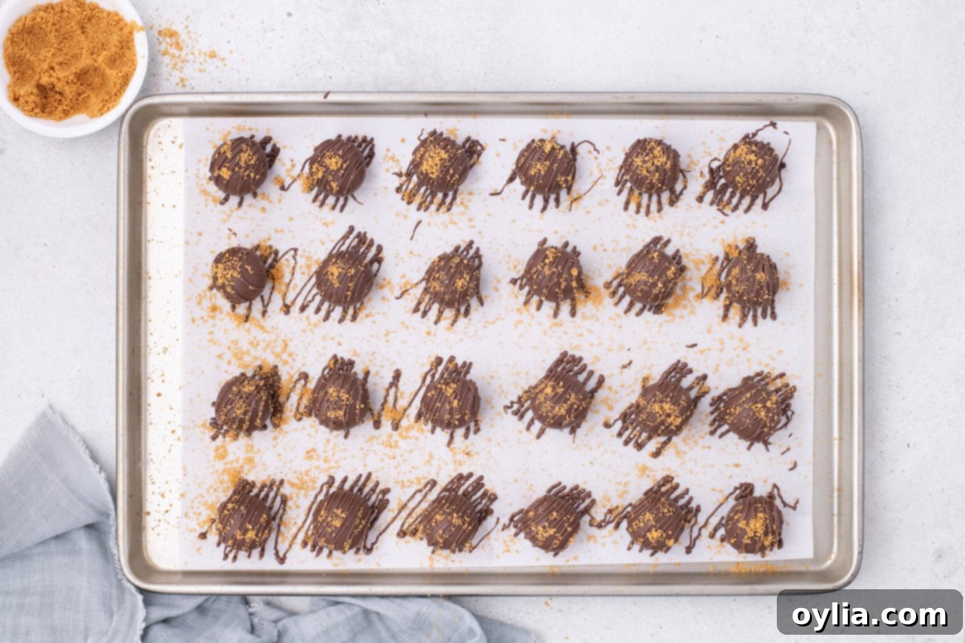 Decorated Nutter Butter balls, drizzled with chocolate and garnished, on a baking sheet.
