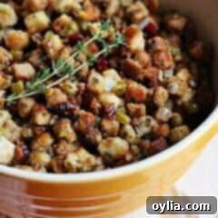 A close up of a bowl of stuffing with parsley, sage, rosemary and thyme, garnished with fresh herbs.