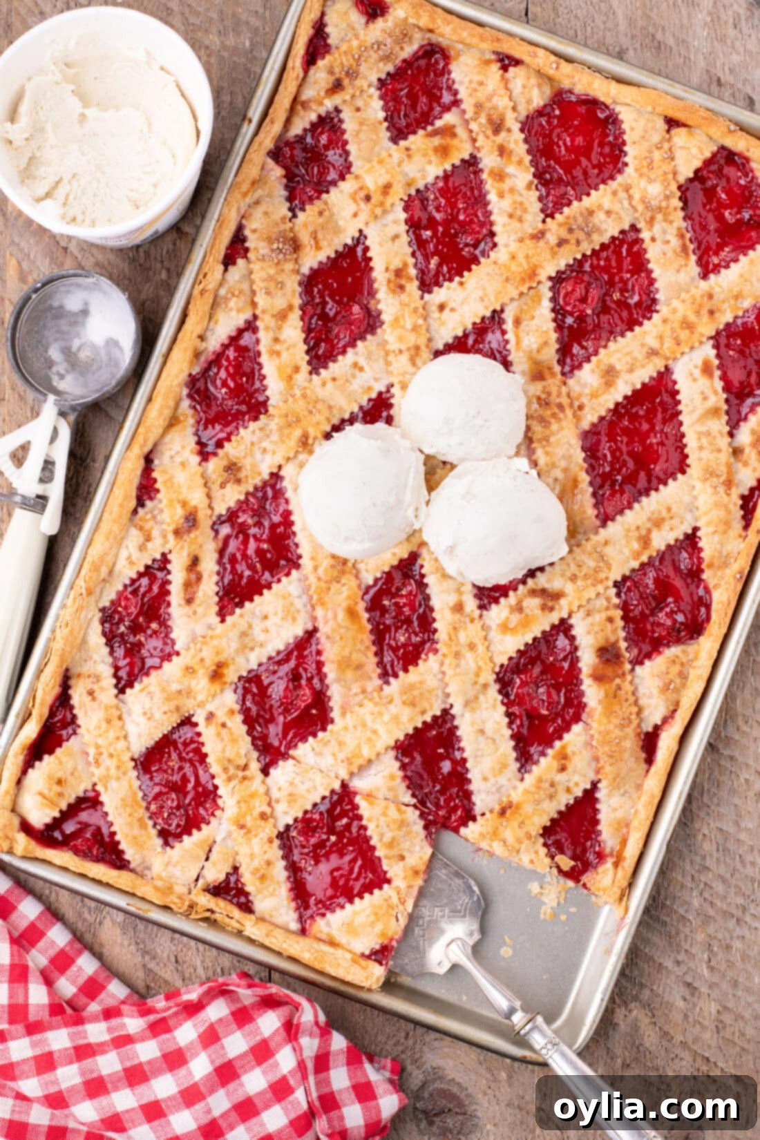 Delicious Cherry Slab Pie topped with three scoops of melting vanilla ice cream, ready to be served at a party or family gathering.