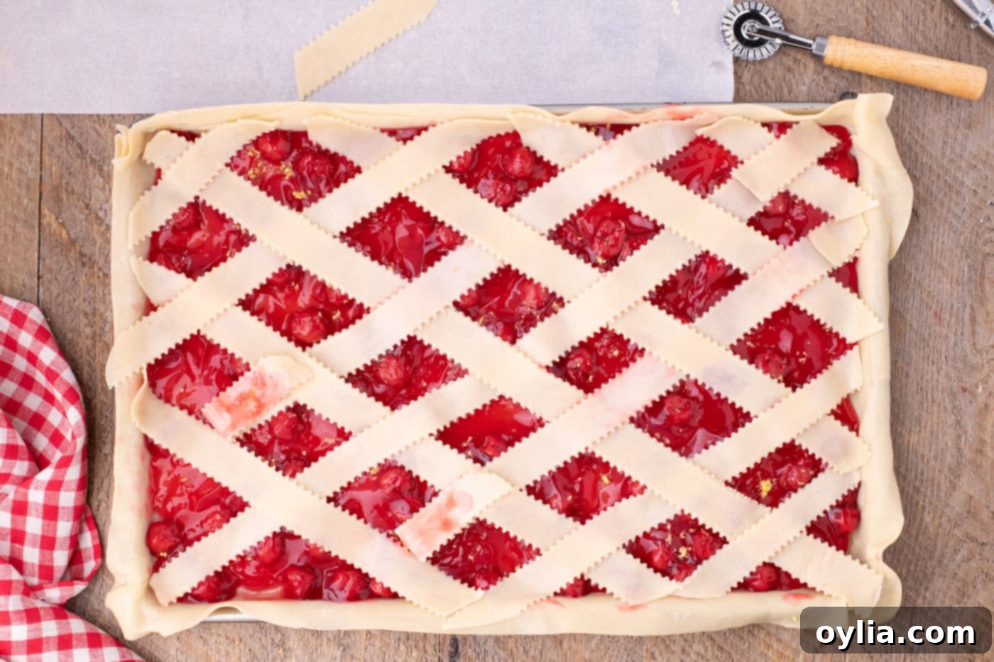 The completed unbaked lattice top of the cherry slab pie, showing the neatly woven crust covering the cherry filling, ready for baking.