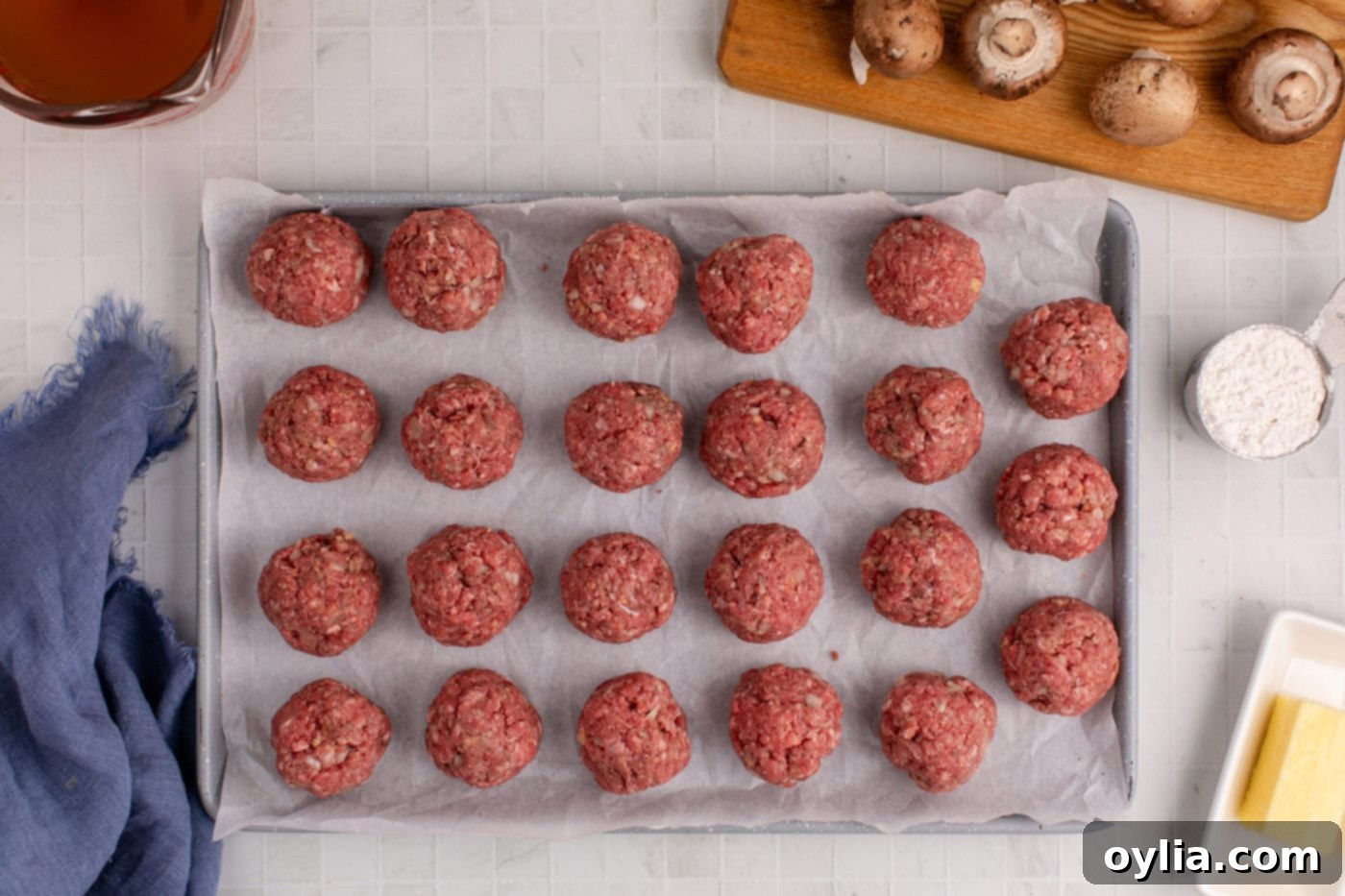 Uniformly shaped meatballs resting on parchment paper, ready to be cooked