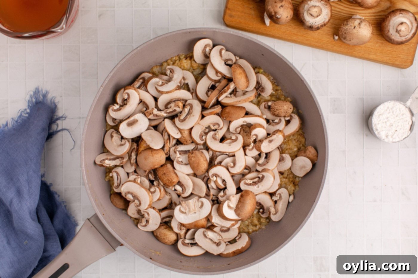 Sliced mushrooms added to the skillet with sauteed onion, cooking until tender and browned