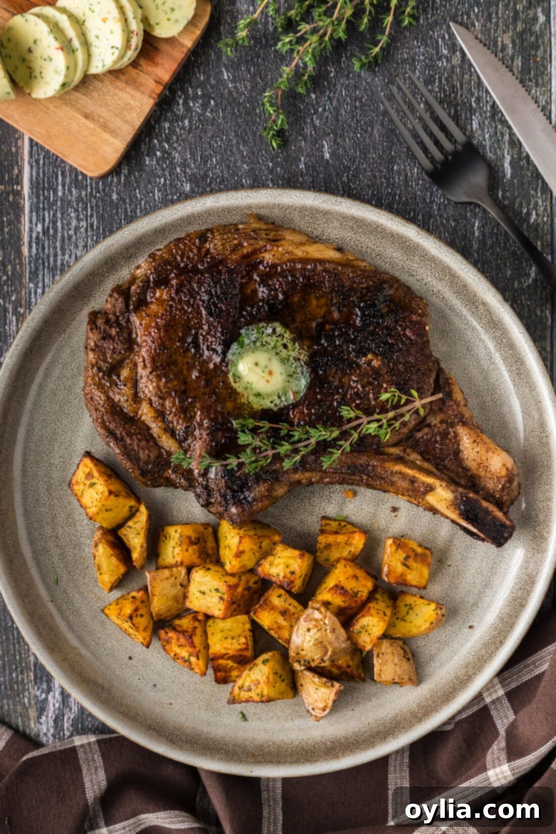 Perfectly cooked bone-in ribeye steak on a plate with crispy cubed potatoes, ready to be enjoyed.