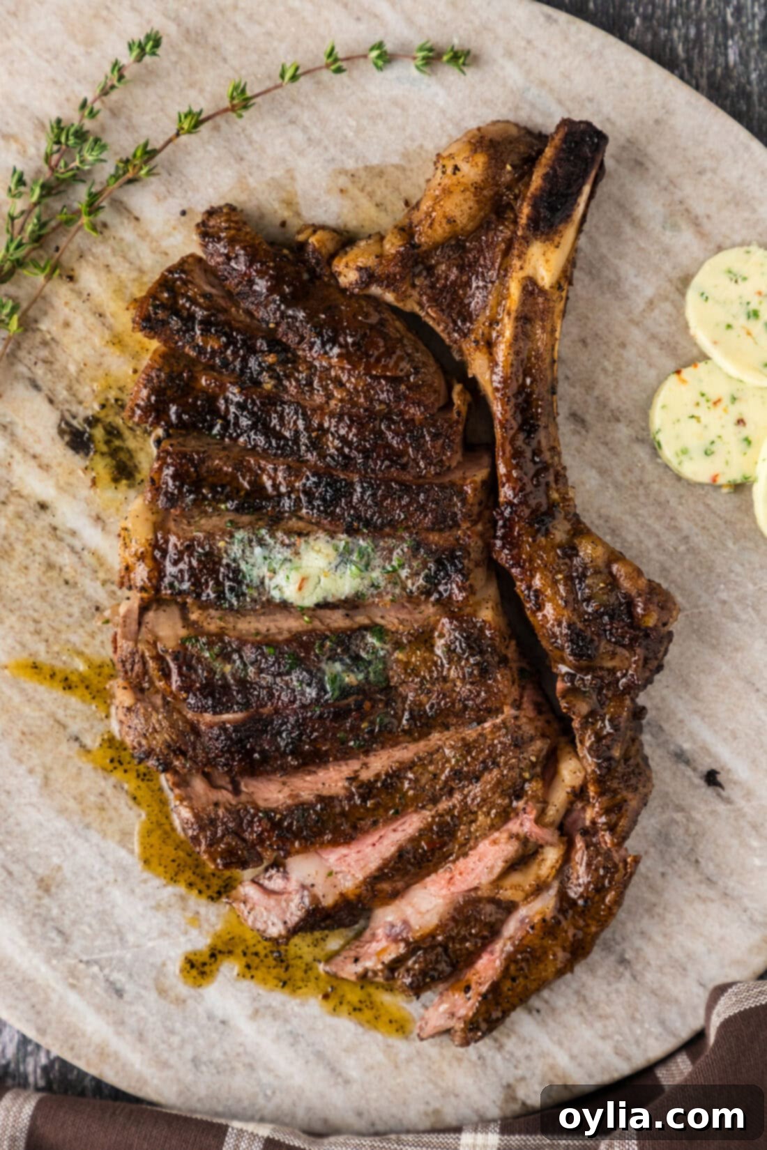 Slices of perfectly cooked bone-in ribeye steak arranged on a marble serving board, showcasing its juicy interior.
