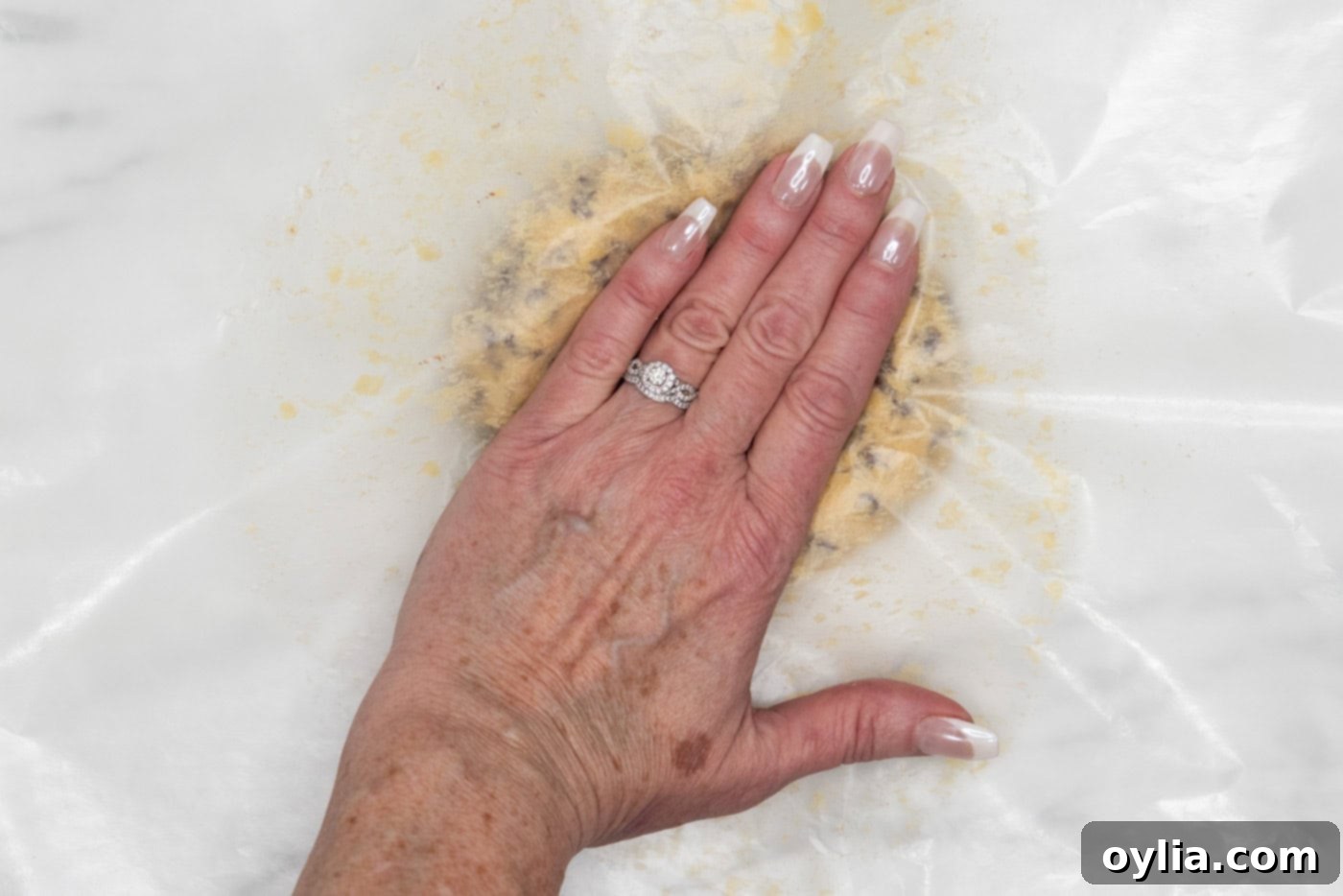 hand flattening cookie dough ball with wax paper