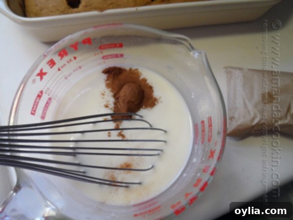 A close up photo of pudding mix, cinnamon and milk in a large measuring cup with a whisk.