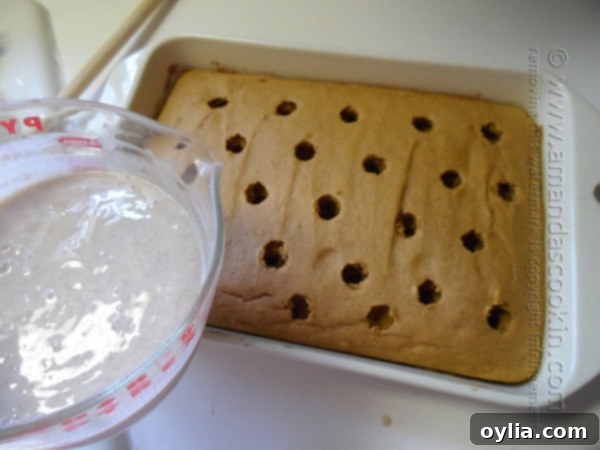 An overhead photo of pumpkin cake in a baking dish with holes and a measuring cup of pudding about to be poured onto the cake.
