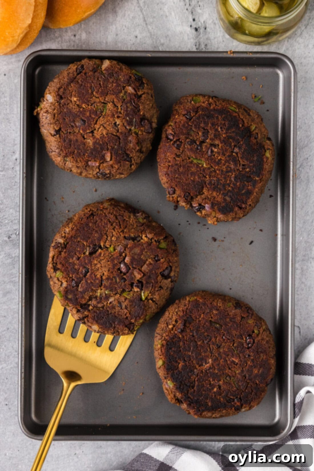 Four Black Bean Burger patties on a baking sheet with a spatula 