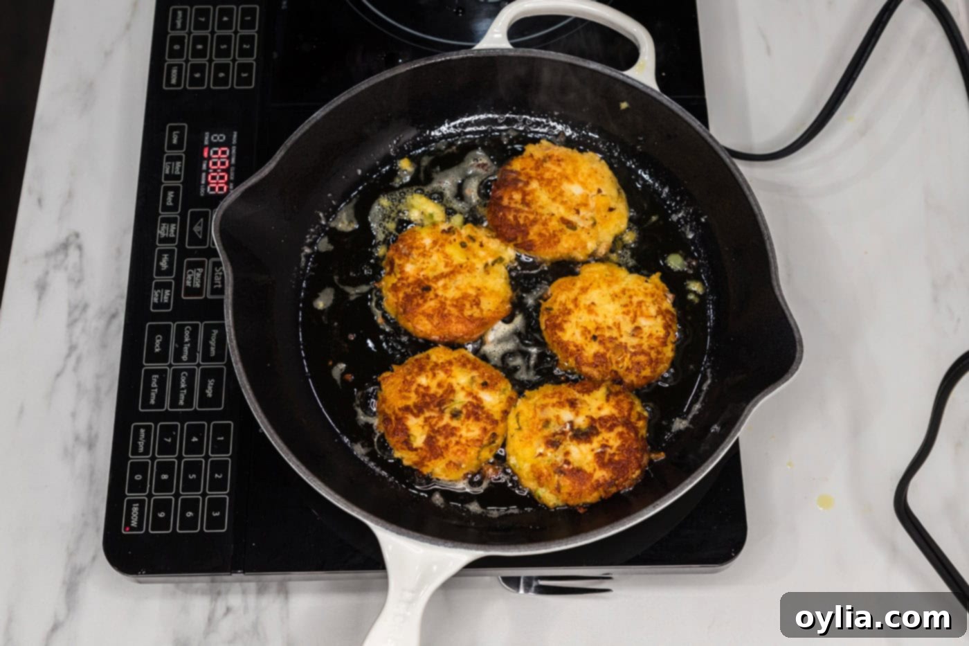 pan fried cod fish cakes in a skillet, turning golden brown
