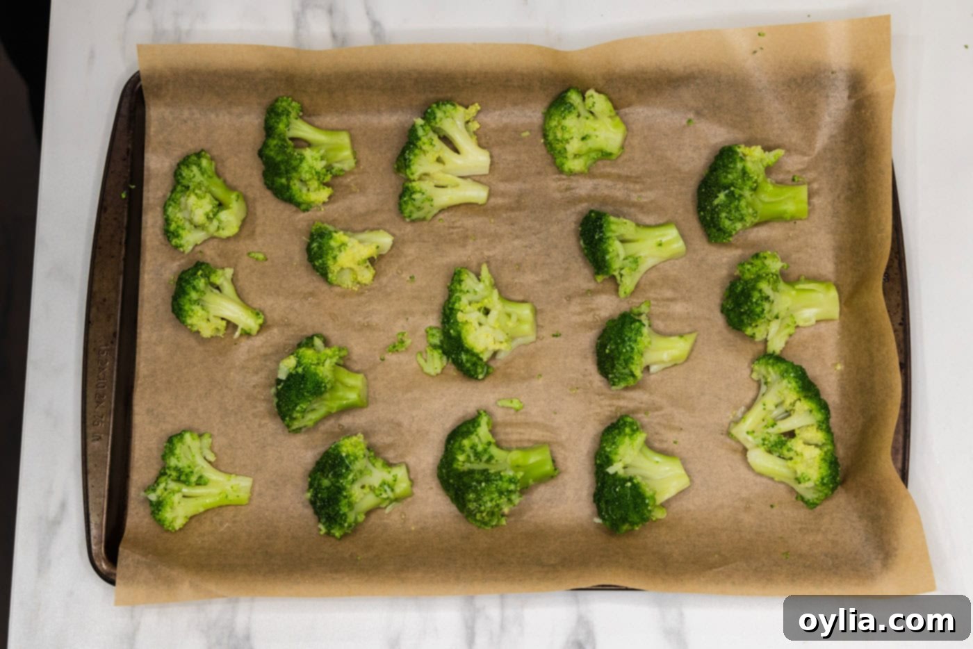broccoli florets on a baking sheet, before and after being smashed with a glass.