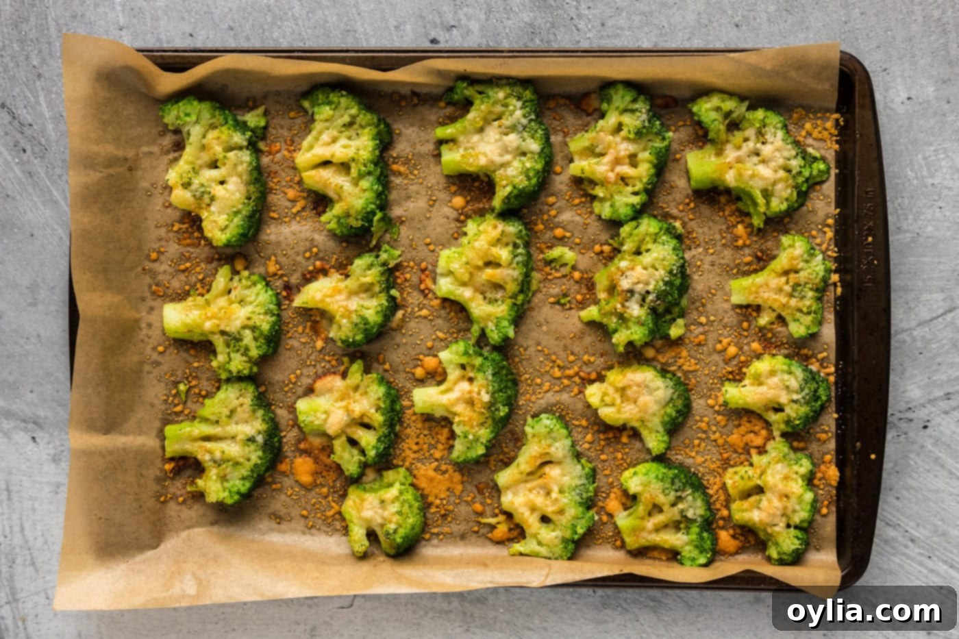 Baked smashed broccoli florets on a baking sheet, golden and crispy.