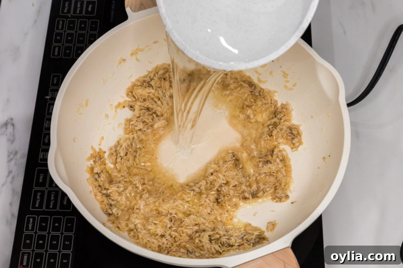 pouring water in skillet with garlic butter rice, preparing for cooking