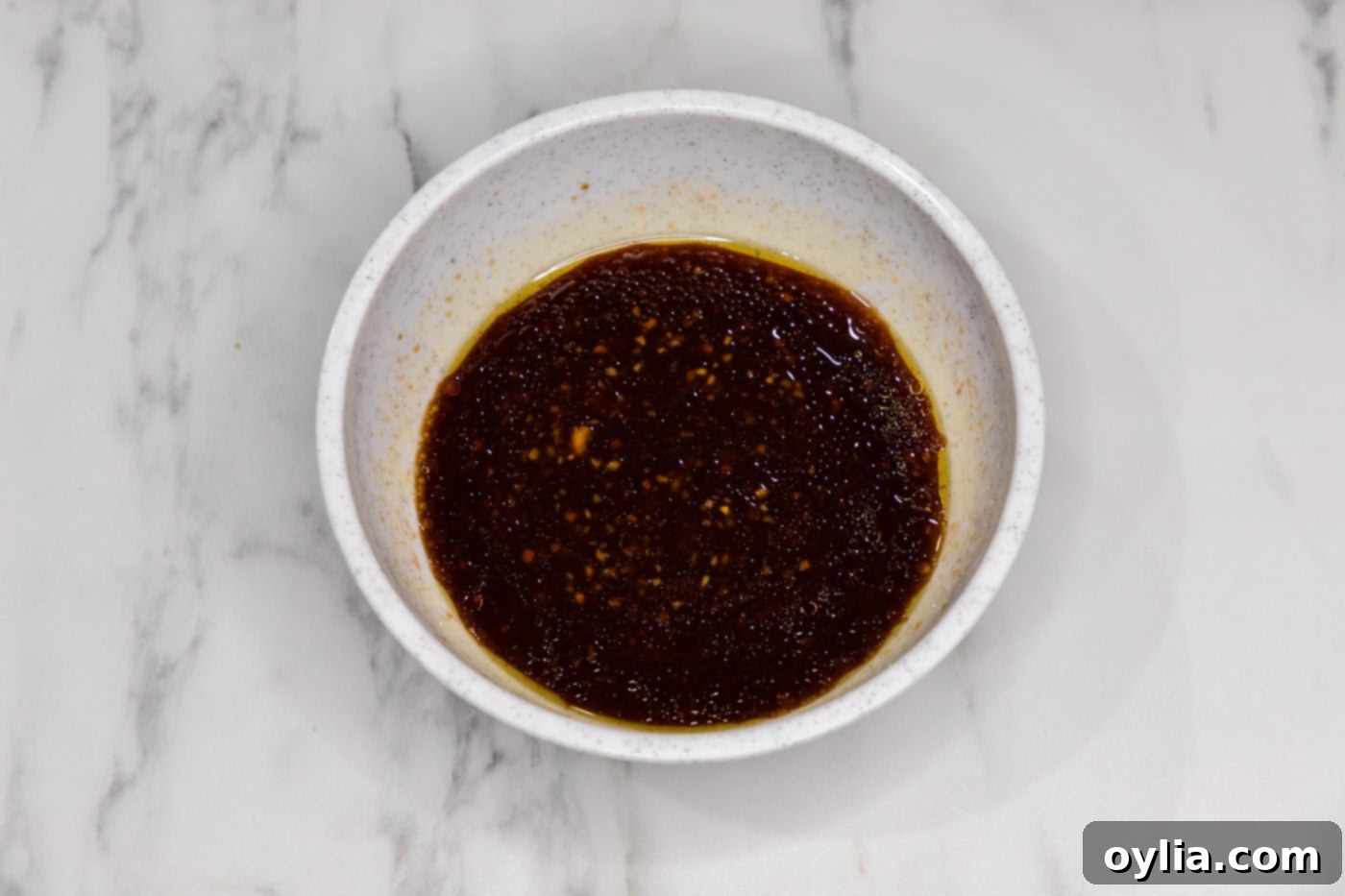 A bowl filled with the whisked bourbon chicken sauce, showing its rich, glossy texture.