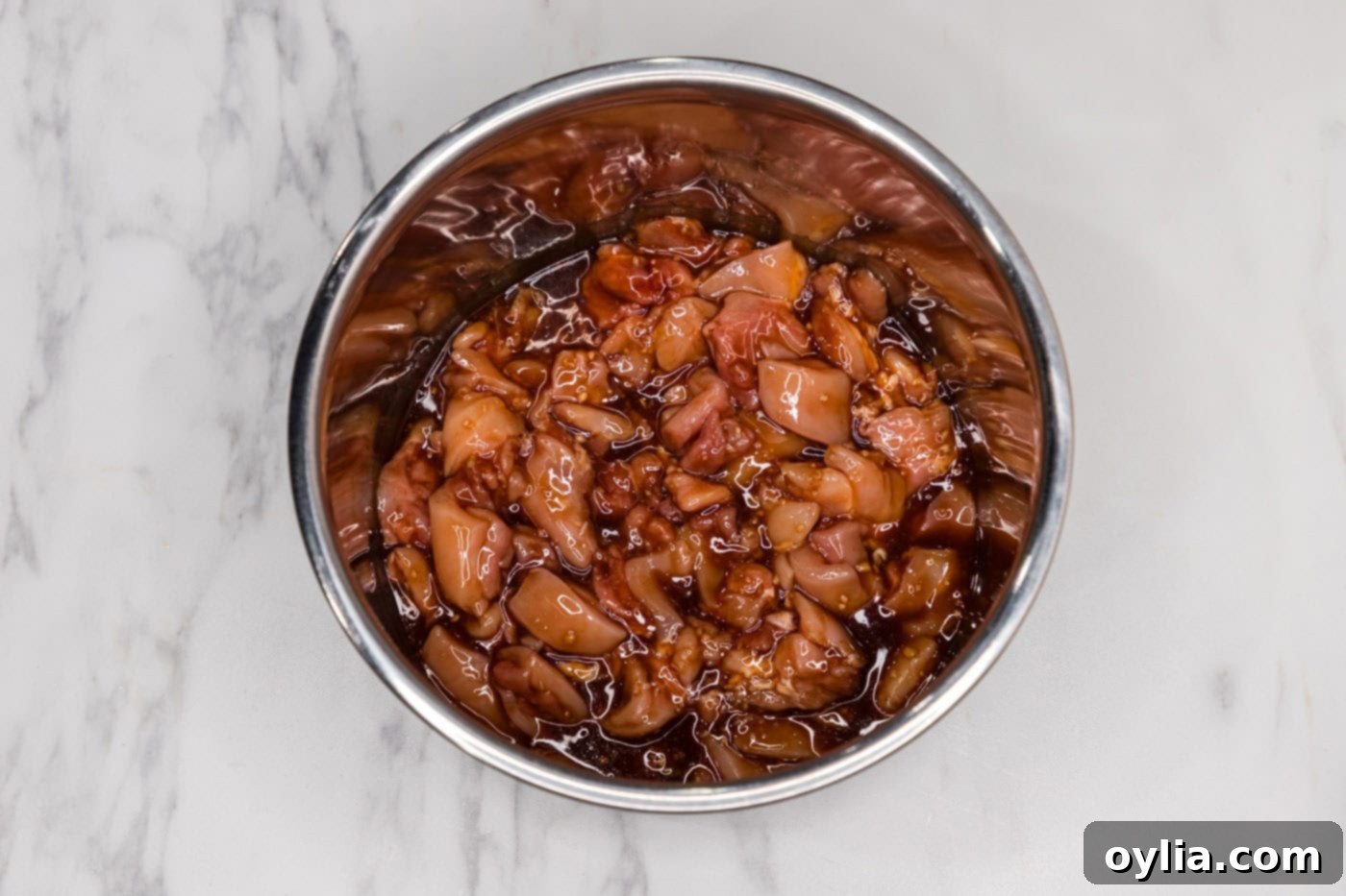 Bite-sized chicken pieces in a bowl, completely coated in the bourbon sauce, ready for the Instant Pot.