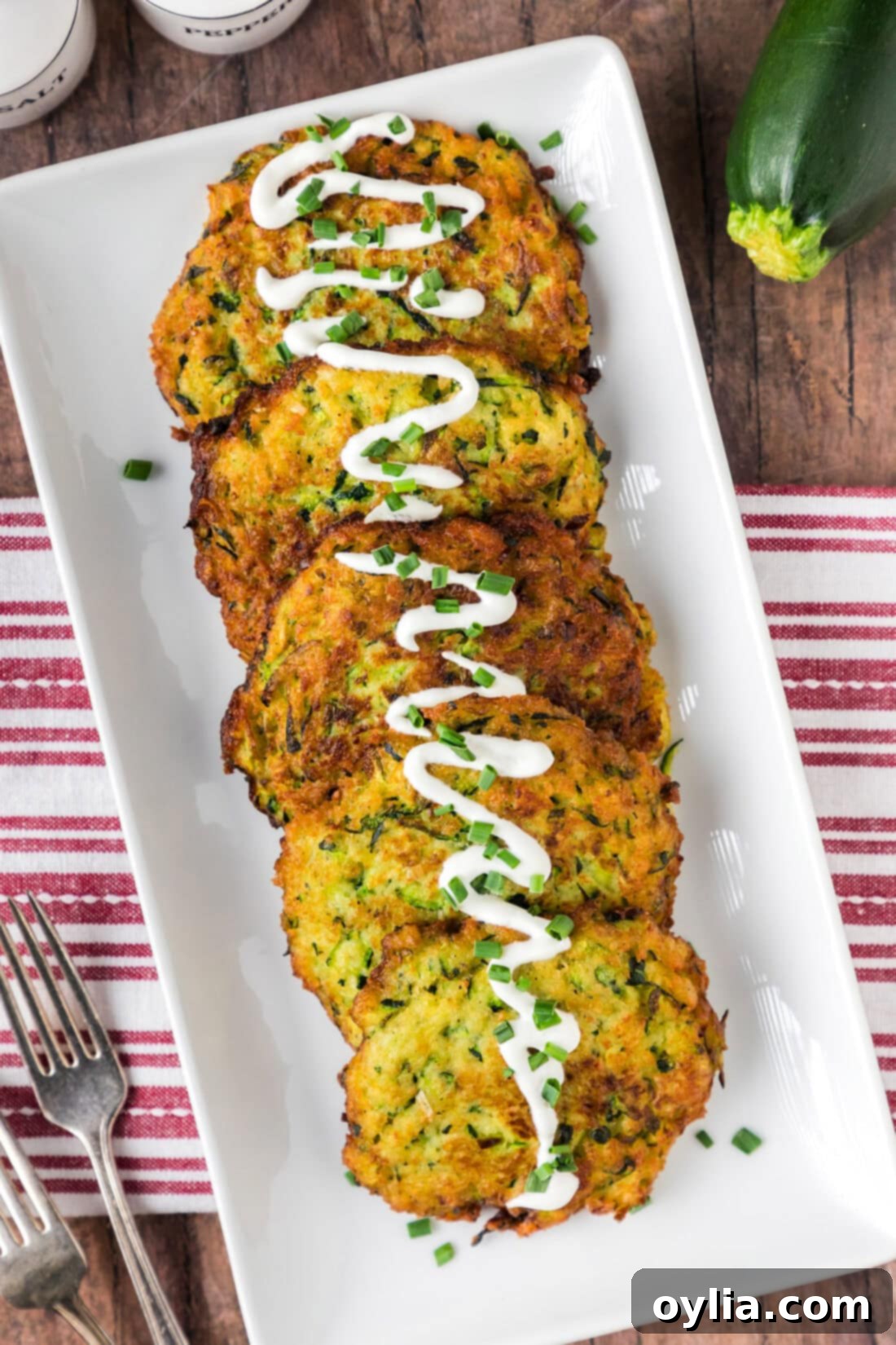 Zucchini Fritters on a platter with sour cream drizzled on top