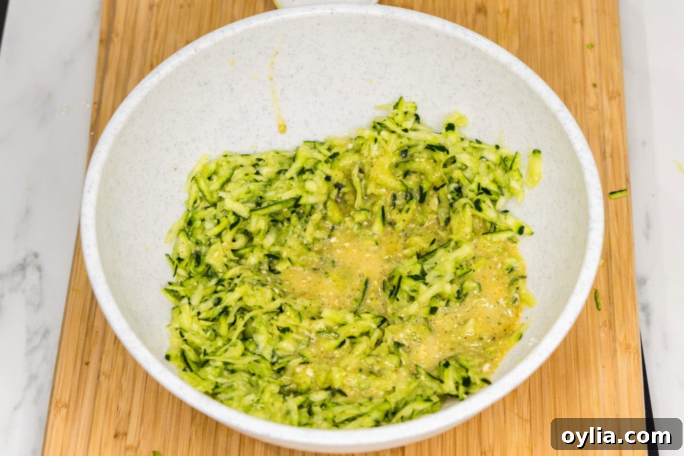 egg added to shredded zucchini in a bowl