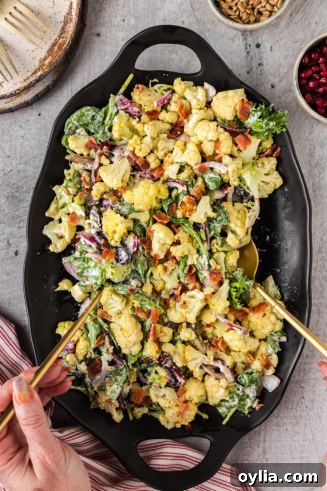 Zesty Cauliflower Salad 10 Hands picking up Cauliflower Salad using serving spoons