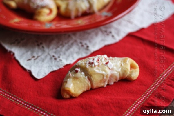 A close up photo of a white chocolate candy cane crescent on a red plate.
