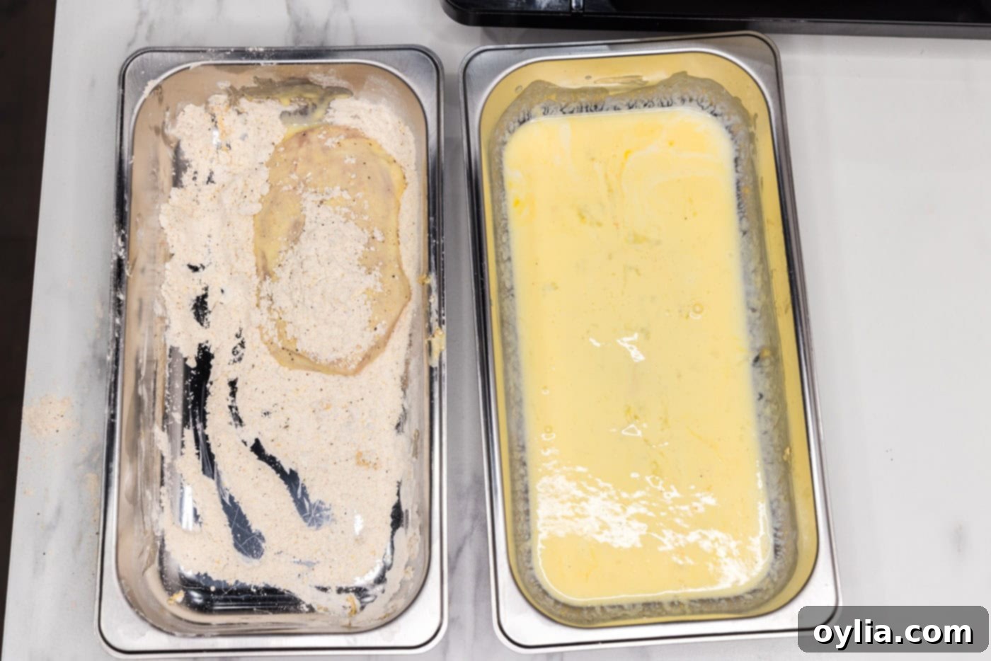 A dredged chicken patty receiving its second coat of flour, ensuring all sides are completely covered for maximum crispiness.