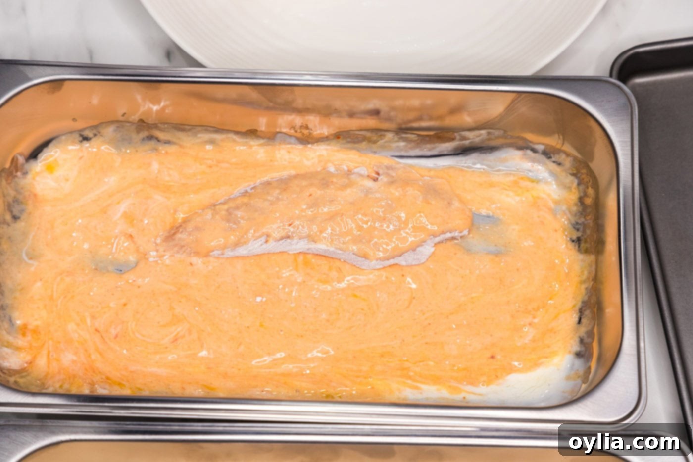 adding flour dredged chicken to pan of buttermilk and hot sauce mixture