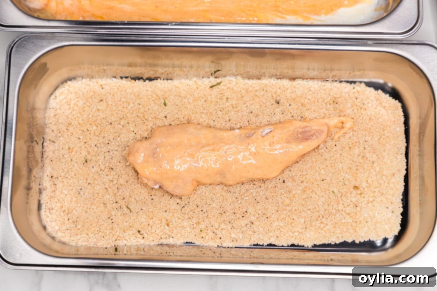 dredged buffalo chicken added to pan of breadcrumb mixture