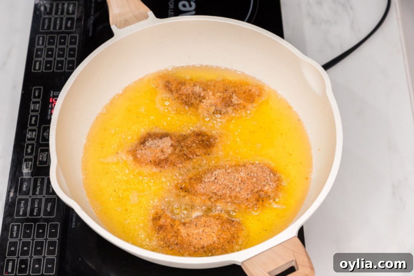 frying buffalo chicken tenders in a skillet of oil
