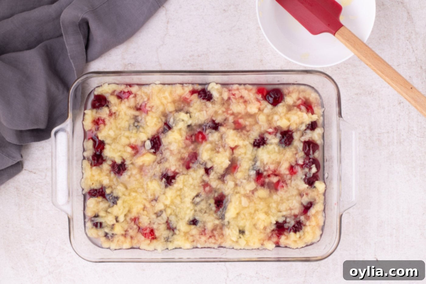 Crushed pineapple with juice poured over the cherry pie filling layer in a baking dish