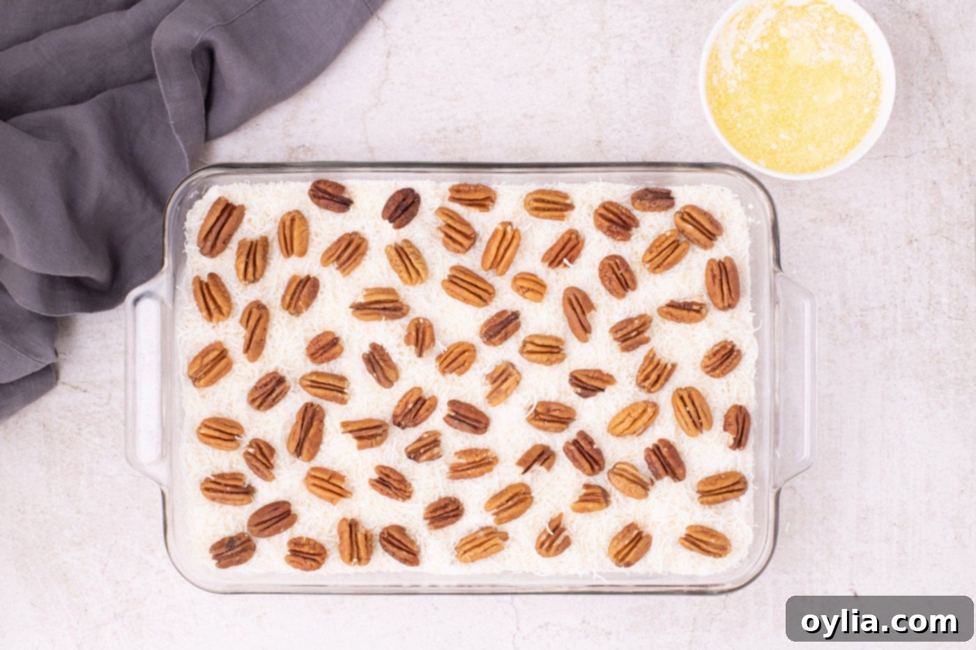 Pecan halves scattered over the shredded coconut and cake mix layers in the baking dish