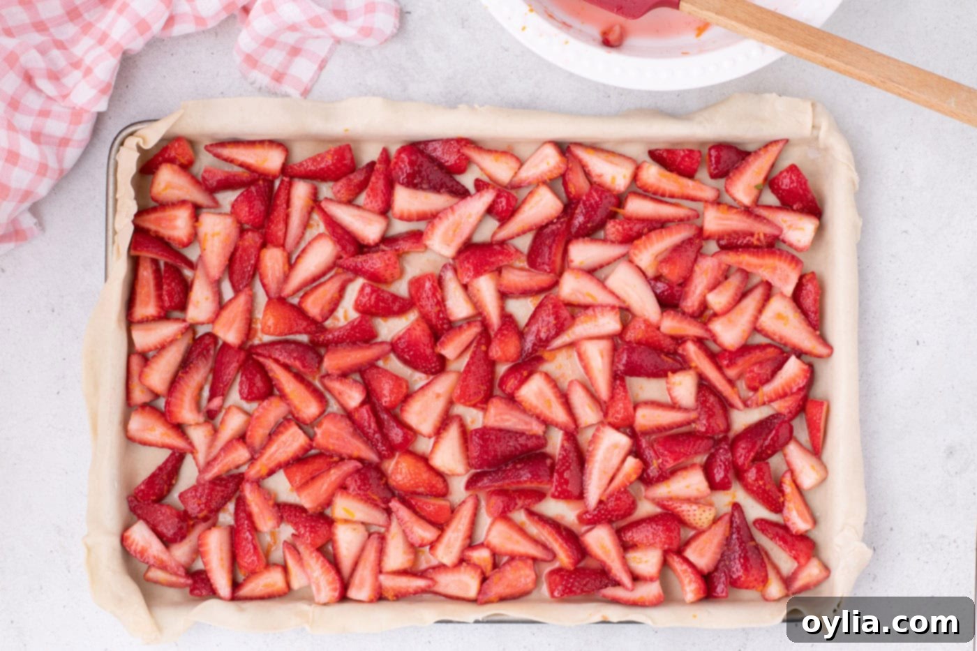 Fresh sliced strawberries and their juices carefully spread over the pie crust in the jelly roll pan.