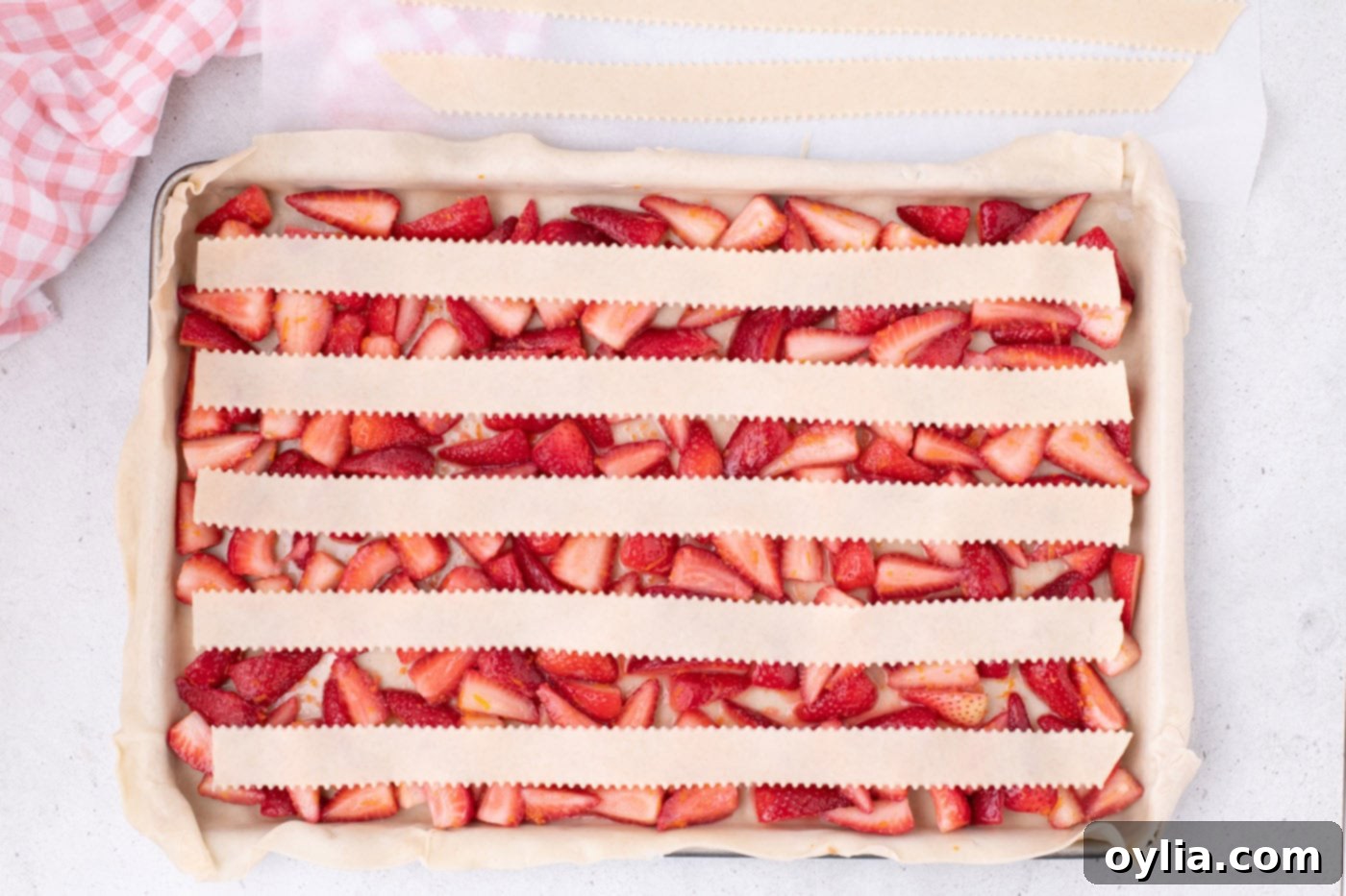Five long strips of pie crust laid horizontally over the strawberry filling in the pan, forming the base of the lattice.