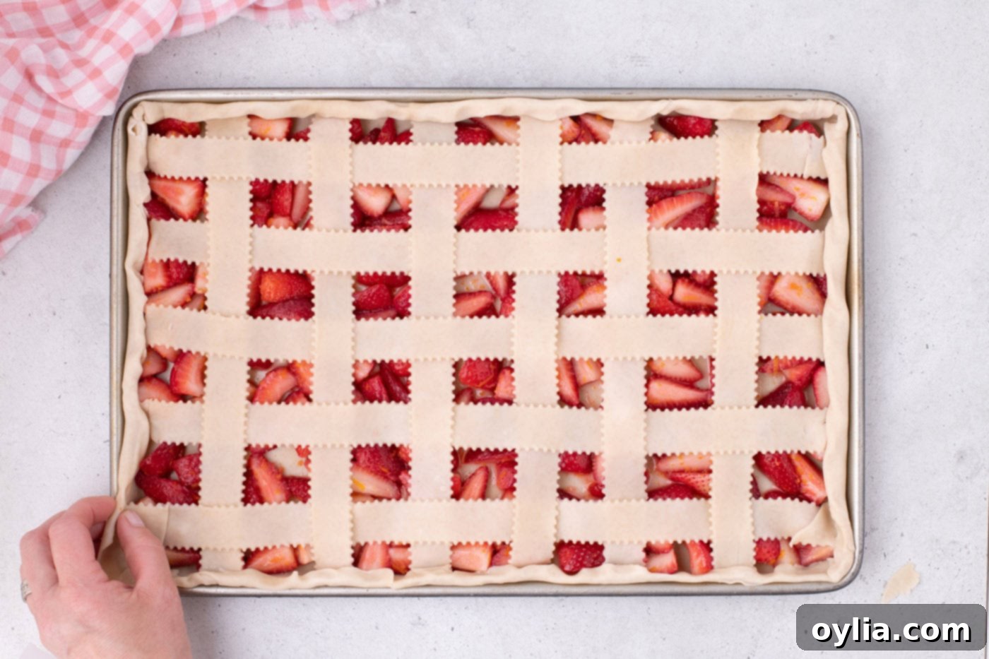 The strawberry slab pie with a fully crimped lattice top, ready for egg wash.