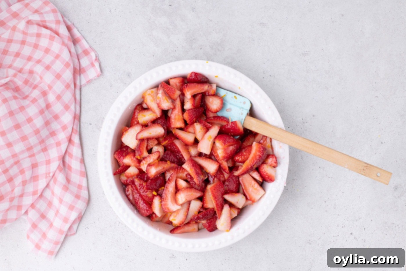 Close-up of sliced strawberries in a bowl, coated with sugar, cornstarch, and citrus zest, ready for the pie.