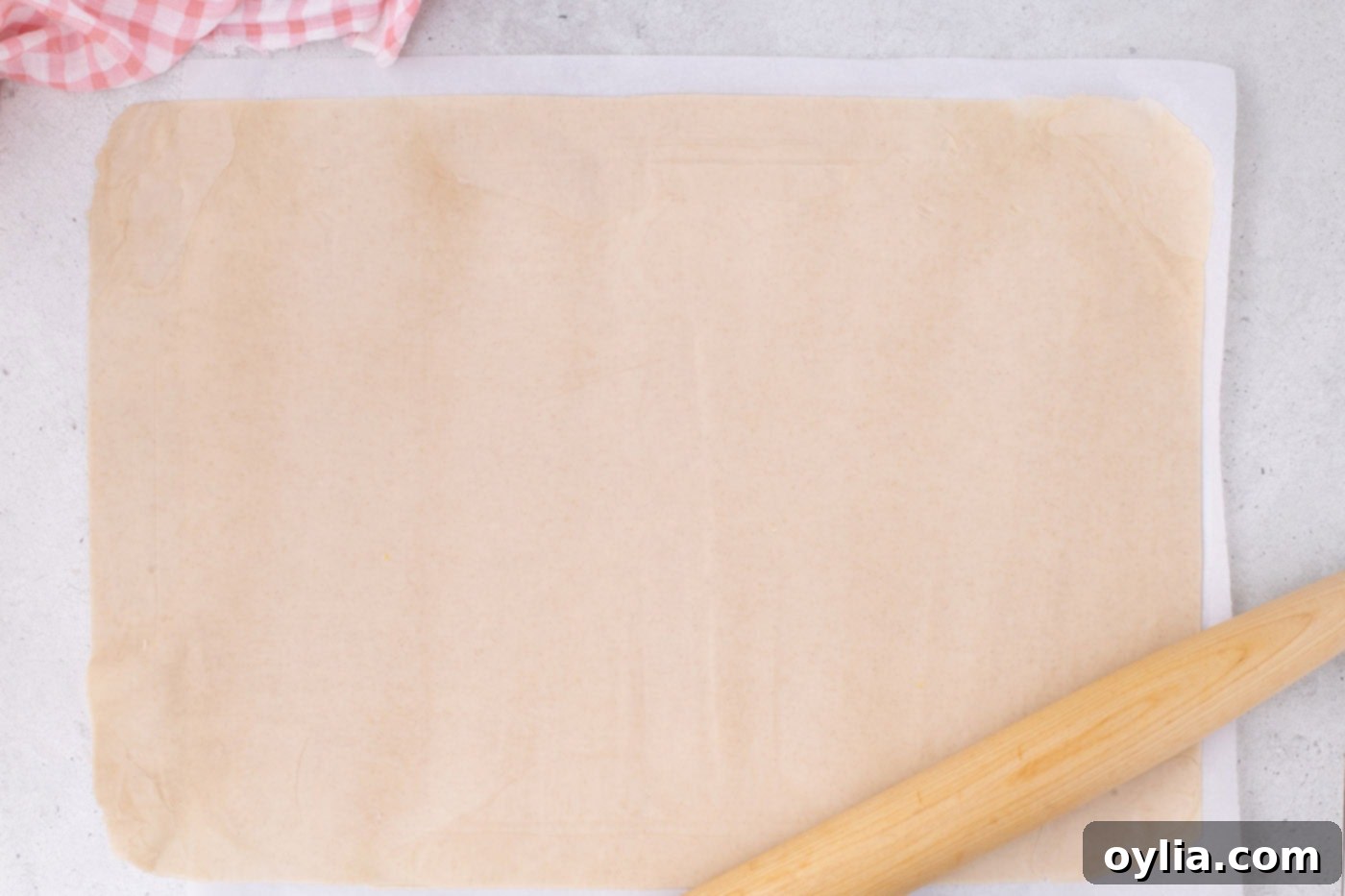 A large, rectangular slab pie crust rolled out, with a rolling pin resting on it.