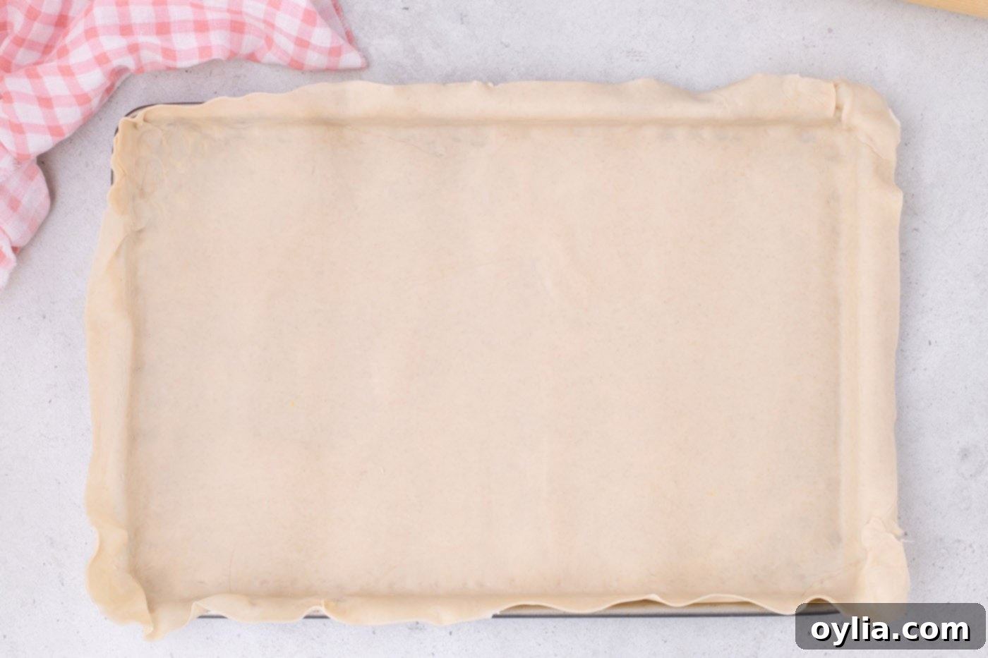 Prepared pie crust neatly placed into a jelly roll pan, ready for filling.
