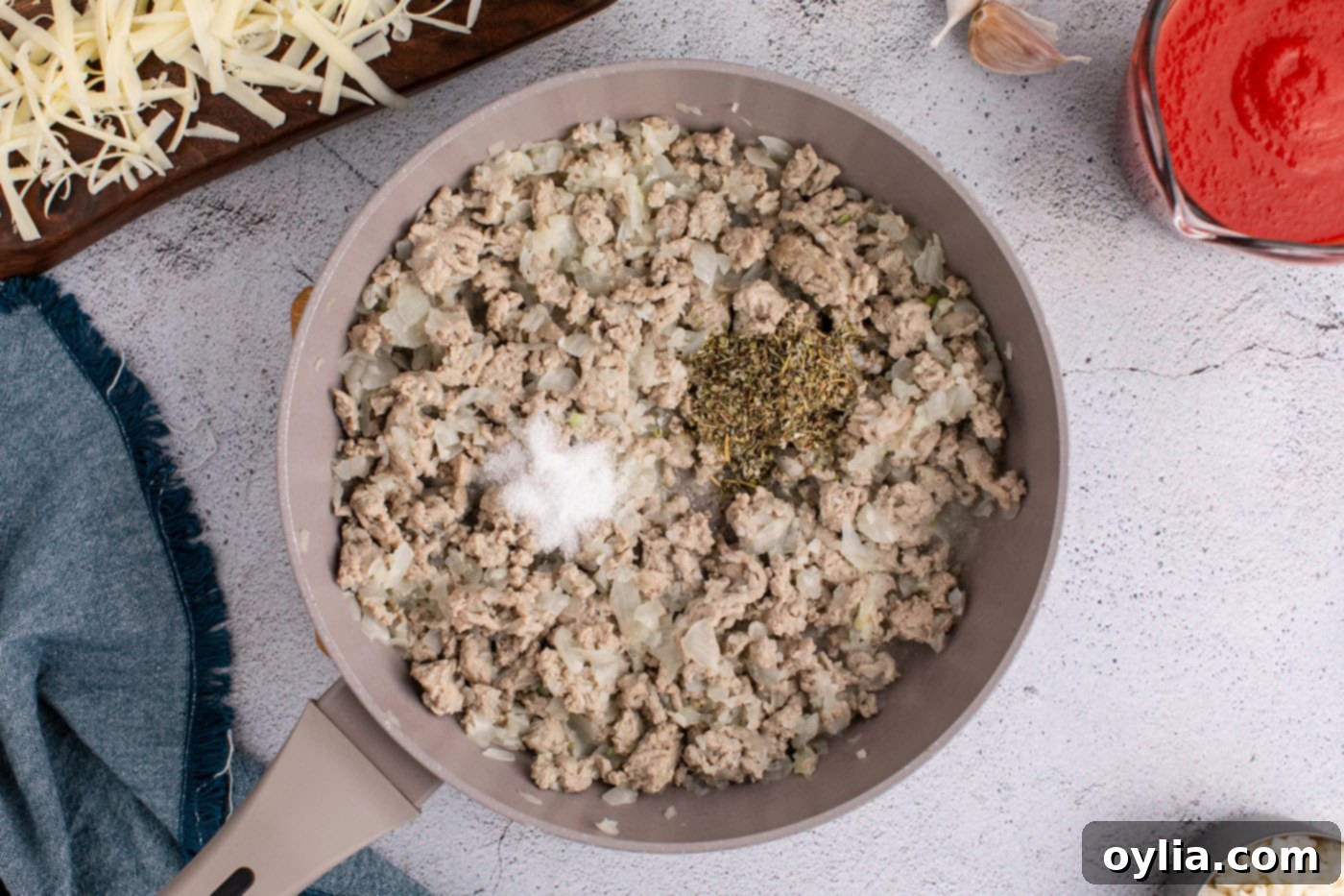 Italian seasoning and sea salt added to the ground turkey and garlic mixture in the skillet, ready to be stirred in.