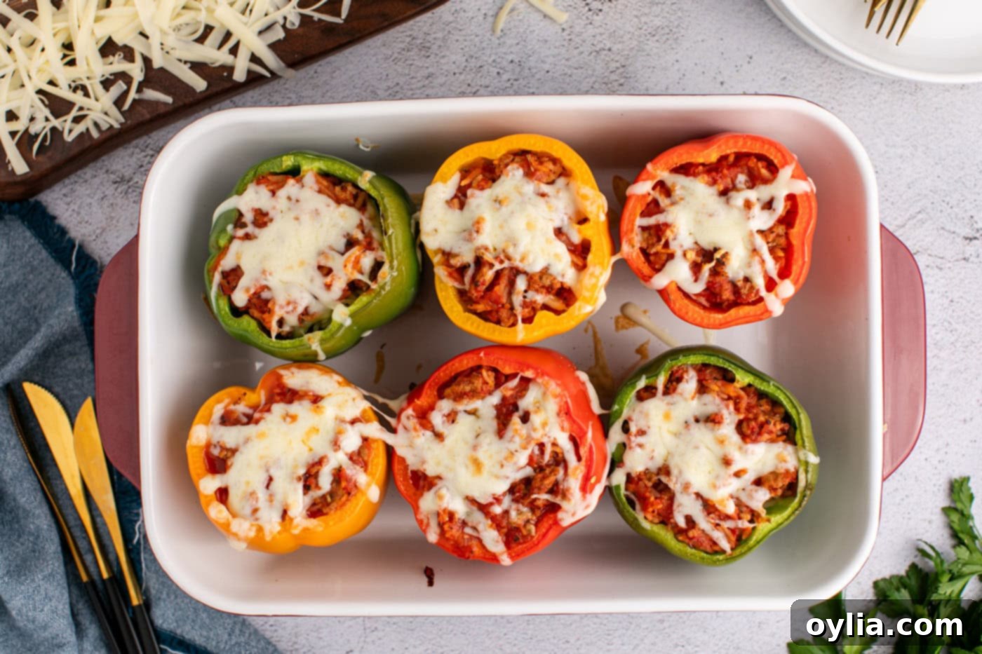 Baked turkey stuffed peppers in a casserole dish, topped with melted, golden-brown mozzarella cheese.