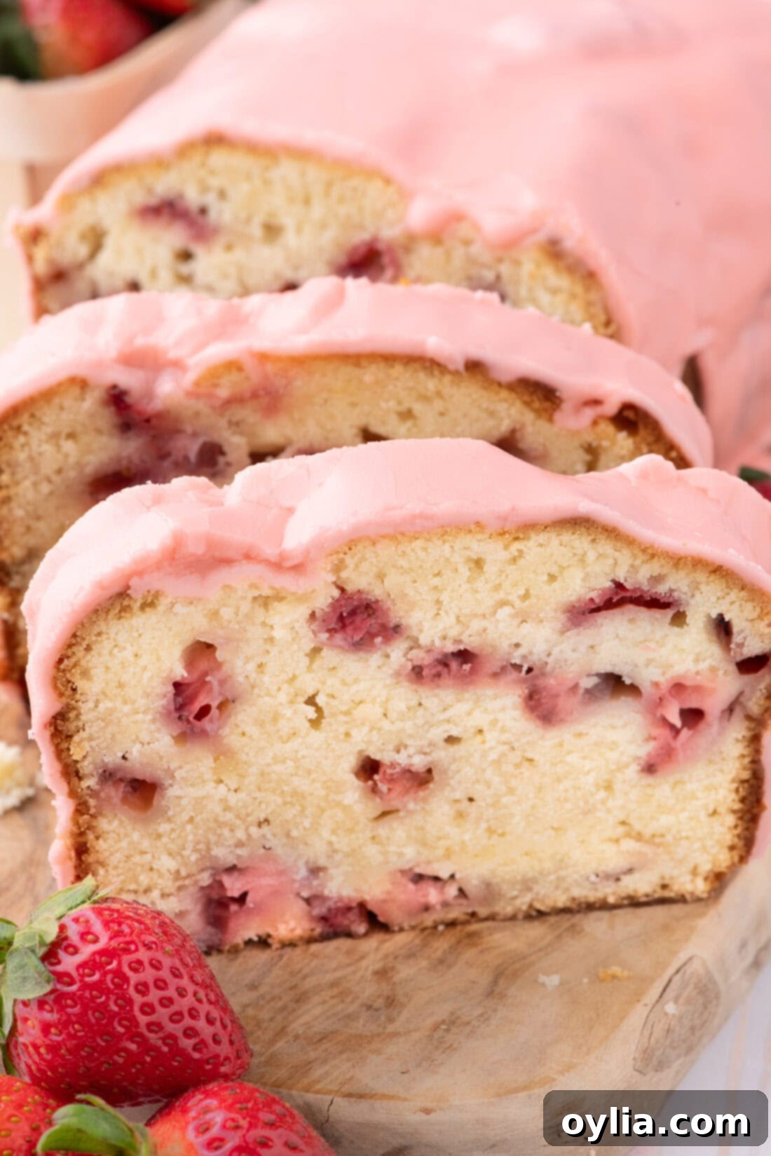 Slices of Strawberry Pound Cake on a wooden board, showcasing its moist texture and berry distribution.