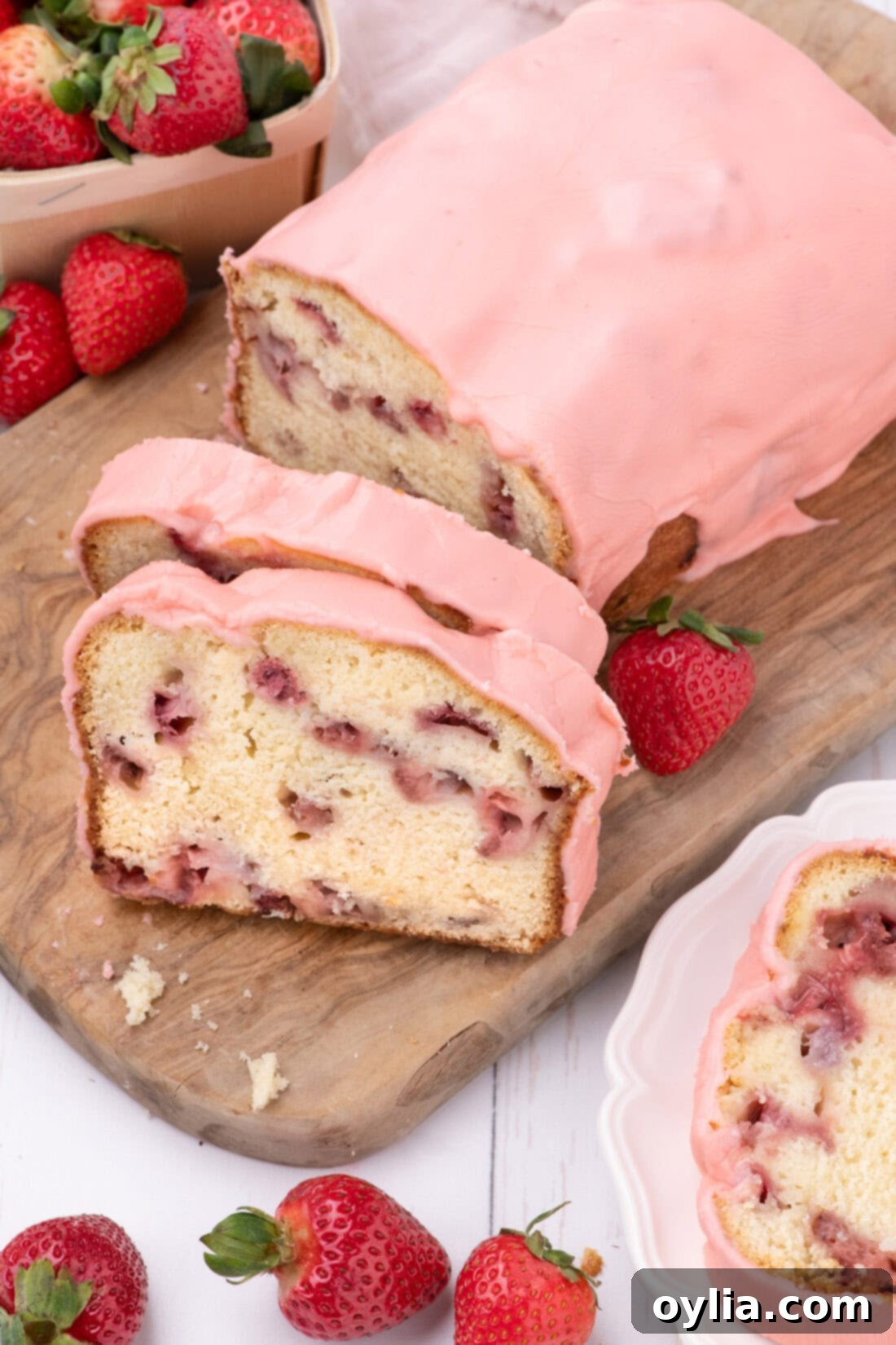 Strawberry Pound Cake on a wooden board with two slices cut, showing the glaze and interior.