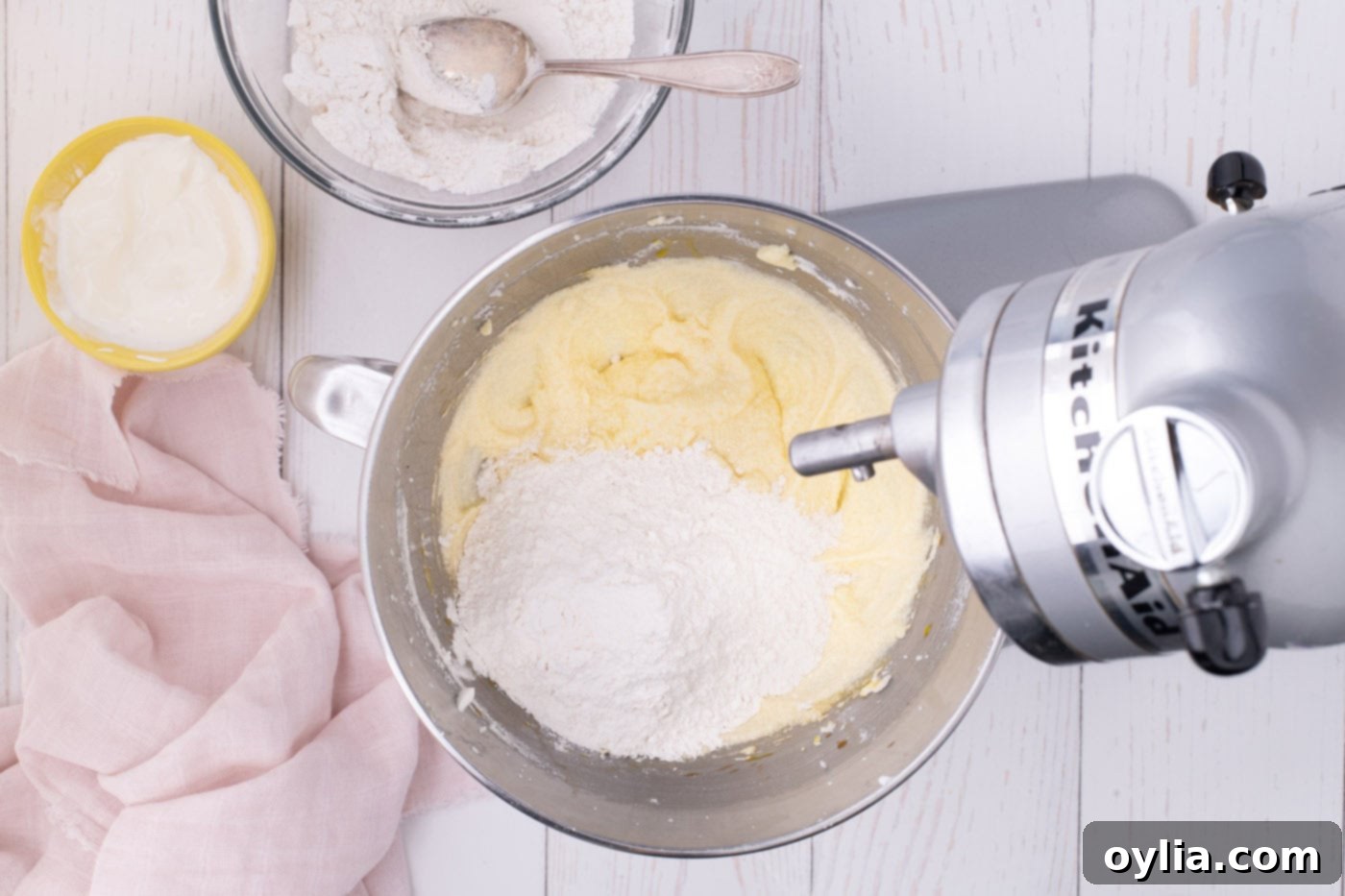 Adding flour mixture to the wet ingredients in a stand mixer bowl, showing the consistency of the batter.