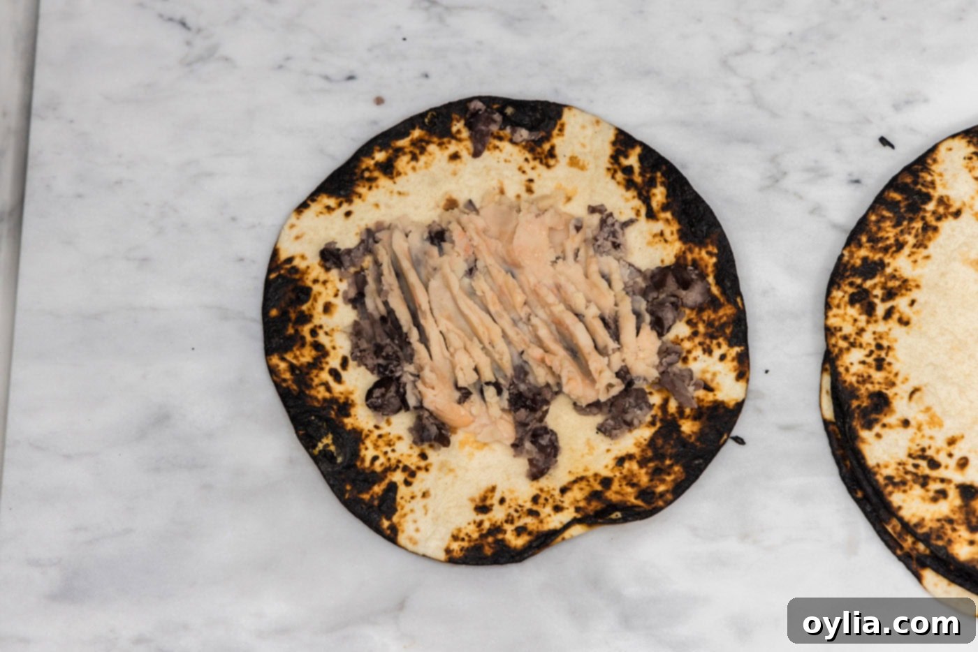 charred tortilla topped with smashed white kidney beans