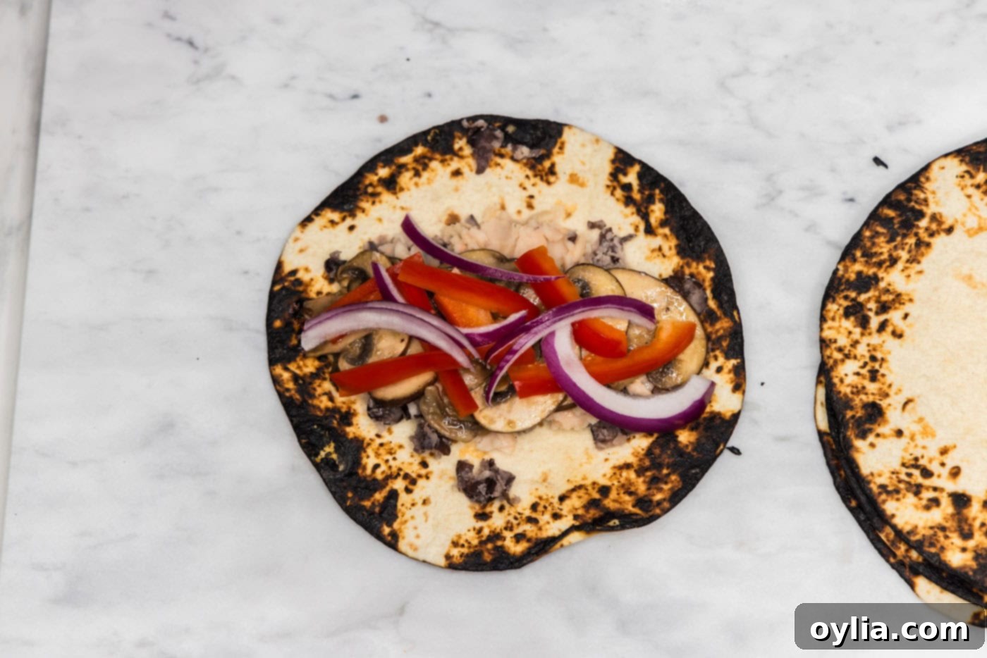 onion, bell peppers, and mushrooms on top of charred tortilla
