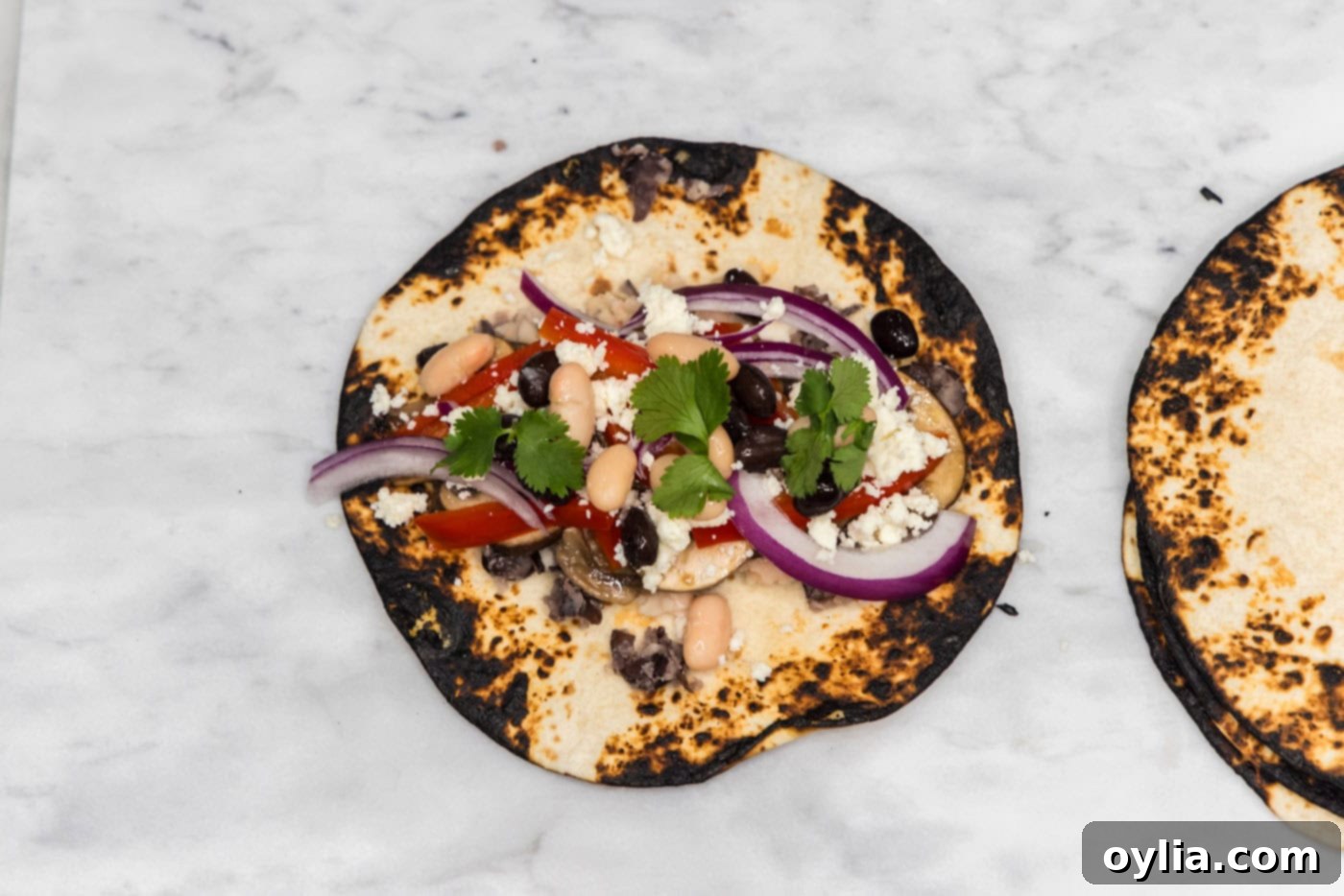 charred tortilla shell topped with fresh vegetables and crumbled queso fresco cheese