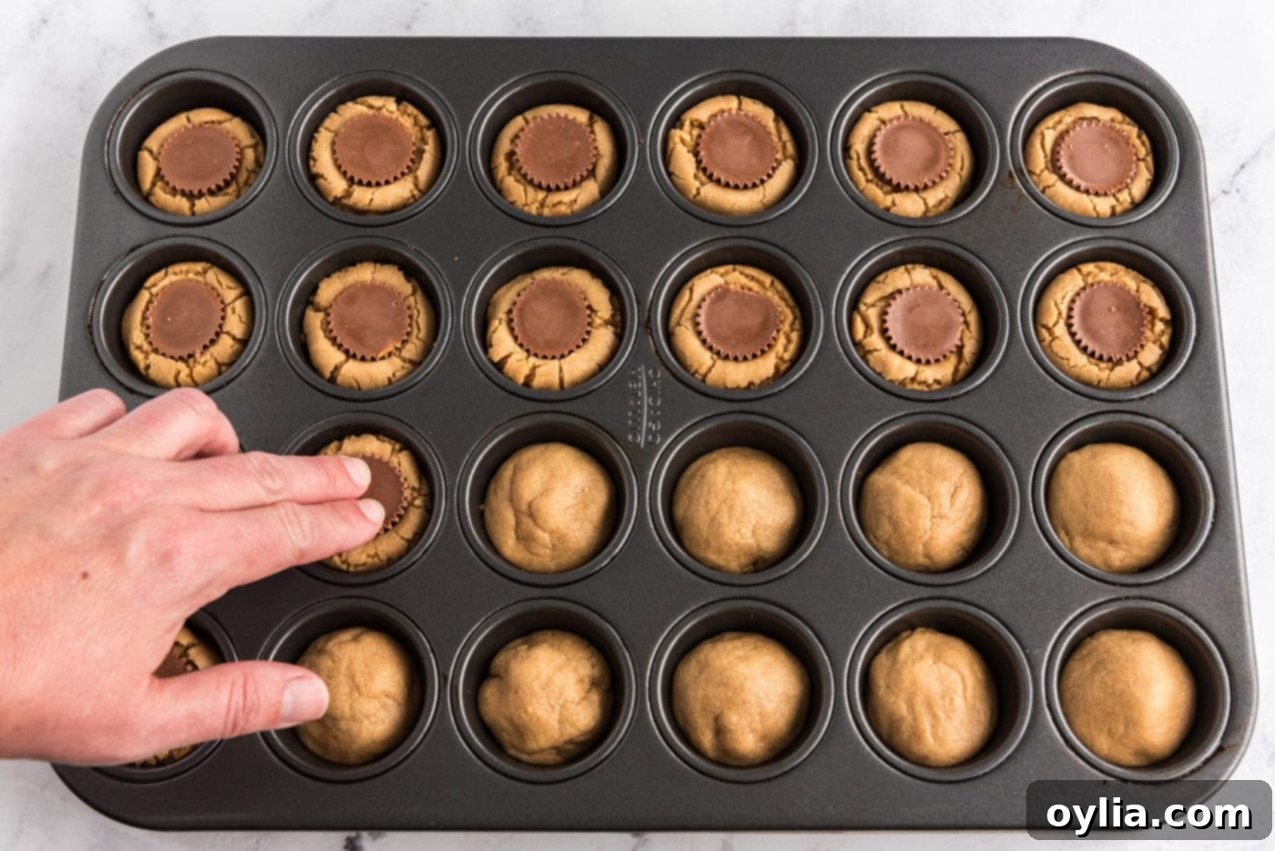 pressing Reeses mini peanut butter cups into peanut butter cookies in a mini muffin pan