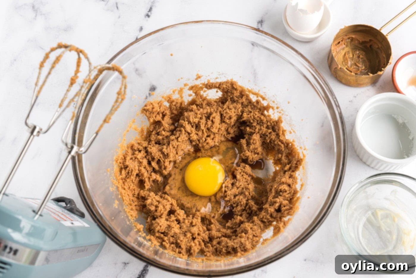 adding egg to peanut butter cookie dough in a mixer bowl